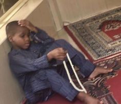 a young boy sitting on the floor with a rope around his neck