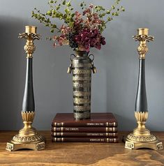 two vases with flowers in them sitting on top of books next to each other