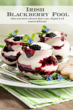 three desserts in small jars with berries and blueberries on top, sitting on a plate