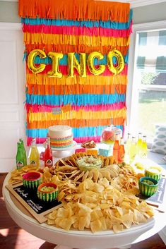 a table topped with chips and guacamole next to a sign that says cinco