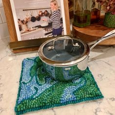 a pot with a lid sitting on top of a kitchen counter next to a cookbook