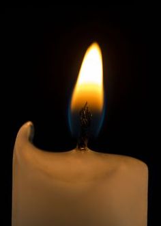 a white candle with a blue flame in the dark