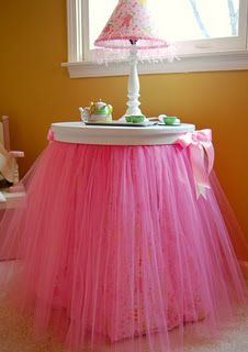 a pink tulle skirted table with tea set on top and cupcakes in the middle