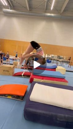 a person is doing tricks on a trampoline in an indoor gymnastics facility while others watch