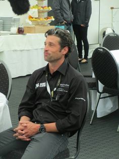 a man sitting in a chair with his hands folded and looking off to the side