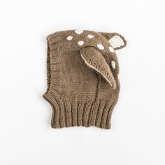 a brown knitted mitt with white polka dots on the side and an elephant's head sticking out of it