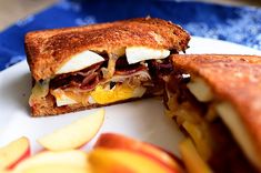 a sandwich cut in half sitting on top of a white plate next to an apple