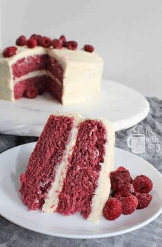 a slice of red velvet cake with white frosting and raspberries on a plate