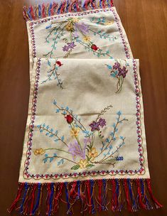 an embroidered table runner with fringes and flowers