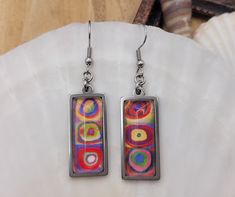 "MYSTERY JEWELRY" GIVEAWAY: Anyone who makes a purchase from Waves of Laguna Jewelry will receive ONE FREE NECKLACE OR SET OF EARRINGS (while supplies last) Take advantage of this offer and add some fun to your purchase! ----------------- These highly unique silver rectangular dangle glass cabochon and stainless steel dangle earrings are inspired by the work of a pioneer of abstract painting, artist Wassily Kandinsky. The image is taken from his well-known drawing, "Color Study. Squares with Concentric Circles" (1913). The pendant tray is a sturdy and sleek stainless steel which gives these earrings a modern, striking and timeless look and is more resistant to tarnishing or rusting compared to other metals. The colors are vibrant and eye-catching. You have the option to choose from two dif Mosaic Pendants, Mystery Jewelry, Jewelry Giveaway, Drawing Color, Color Study, Concentric Circles, Modern Abstract Art, Painting Artist, Color Studies