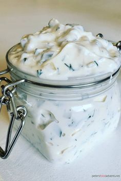 a jar filled with white liquid sitting on top of a table next to a spoon