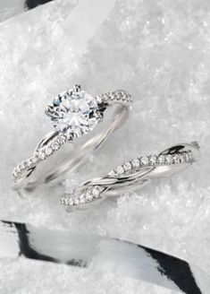 two white gold wedding rings with diamonds in them on snow covered ground, close up