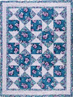 a blue and white quilt with pink flowers on the center, in front of a green background