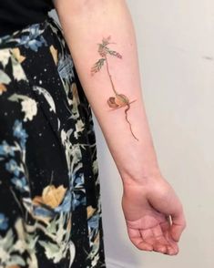 a woman's arm with a small flower tattoo on the left side of her arm