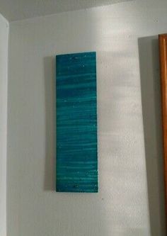 a blue piece of art hanging on the wall next to a wooden frame and mirror