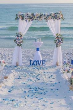 an outdoor wedding setup on the beach with confetti and blue flowers in the sand