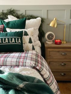 a bed with green and white pillows on top of it next to a night stand