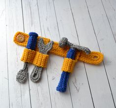 two crocheted toy wrenches on top of a white wooden floor next to a pair of scissors