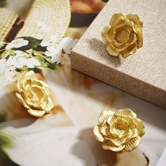 two gold flowers sitting on top of a table next to a box