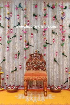 a chair sitting in front of a wall with flowers and beads hanging from it's sides