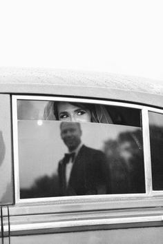 a black and white photo of a woman in a car looking out the window