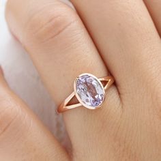 a woman's hand wearing a ring with an oval shaped purple stone on it