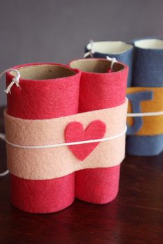 three small cups with hearts on them sitting on top of a wooden table next to twine