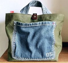 a green bag with a blue jean pocket on it's side and a brown leather handle