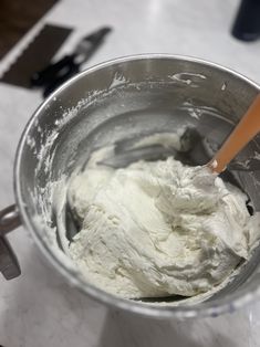 a metal bowl filled with whipped cream on top of a counter