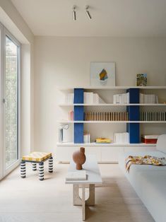 a living room filled with furniture and bookshelves next to a large glass window