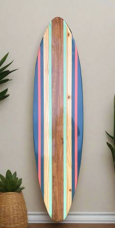 a wooden surfboard sitting on top of a wall next to some potted plants