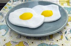 two fried eggs on a blue plate with yellow yolks in the middle and an elephant print tablecloth