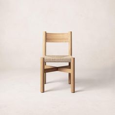 a wooden chair sitting on top of a white floor next to a gray wall with a light colored seat