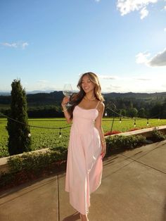 a woman in a pink dress holding a glass of wine