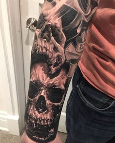 a man's arm with a skull and motorcycle helmet tattoo on his left arm