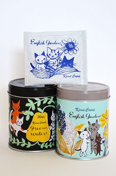 three small tins with labels on them sitting next to each other in front of a white background