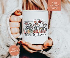 a woman is holding a coffee mug with the words librarian on it and flowers in front of her