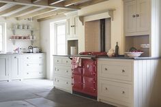 a large kitchen with white cabinets and red stove