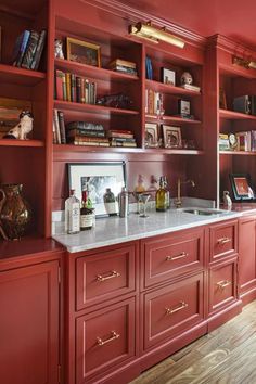 a kitchen with red cabinets and marble counter tops