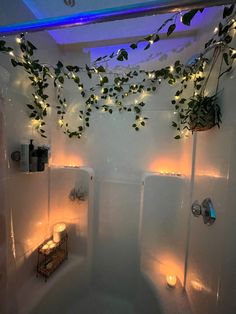 a bathroom with plants and candles on the wall above the bathtub, along with lights