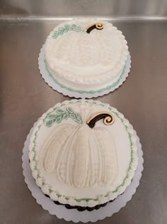 two decorated cakes sitting on top of a metal counter