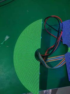 an electronic device is laying on top of a green surface with white dots and wires