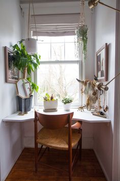 a room with a window, chair and plants on the windowsill in front of it