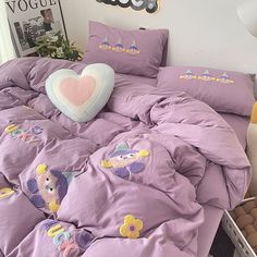 a bed with purple comforter and pillows on it