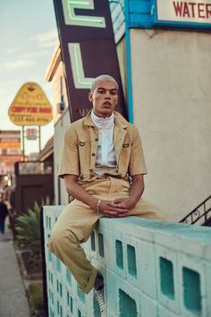 a man sitting on the side of a building next to a sign that says water