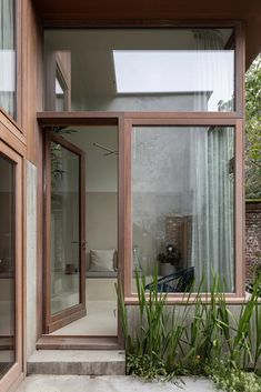 an open living room with sliding glass doors and plants in the foreground, outside