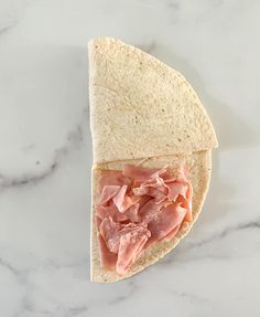 a tortilla with ham and cheese on it sitting on a marble counter top