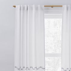 a white curtain with blue trim hanging in front of a window