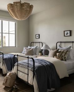 a bedroom with two beds and a suitcase on the floor in front of a window