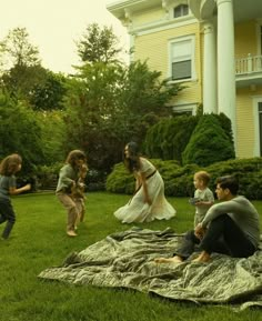 a group of people sitting on top of a lush green field next to a house